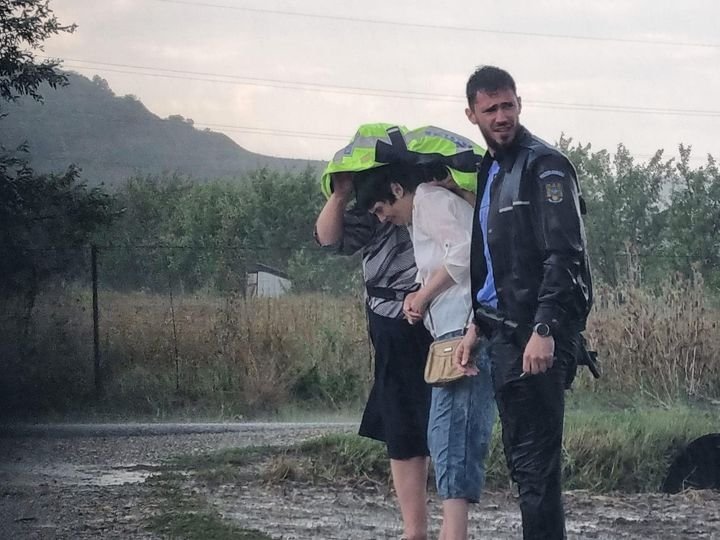 IMAGINEA ZILEI vine de la Cluj: Un polițist și-a oferit haina unor femei pentru a le feri de ploaie